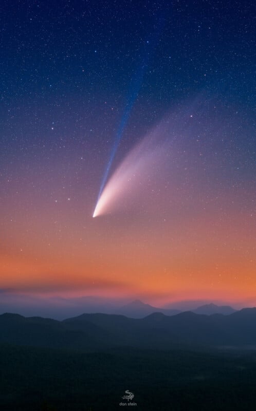 A bright comet with a long tail streaks across a starry sky at twilight. The horizon displays a gradient of colors from deep blue to orange, silhouetting distant mountain ranges.