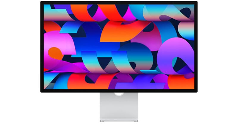 A computer monitor displaying a vibrant abstract wallpaper with a mix of bright colors, including red, blue, purple, and orange, in swirling and layered patterns. The monitor has a sleek, modern design with a silver stand.