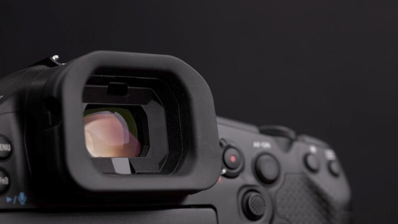 Close-up of a camera viewfinder and control buttons against a dark background. The focus is on the eyepiece, showing the camera's details and texture.