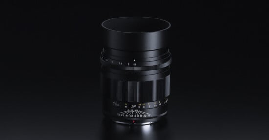 Black camera lens isolated on a dark background with visible focus scale and aperture settings.