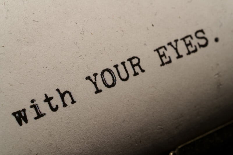 Close-up of the words "with YOUR EYES." typed on a textured, off-white paper, suggesting use of a typewriter.