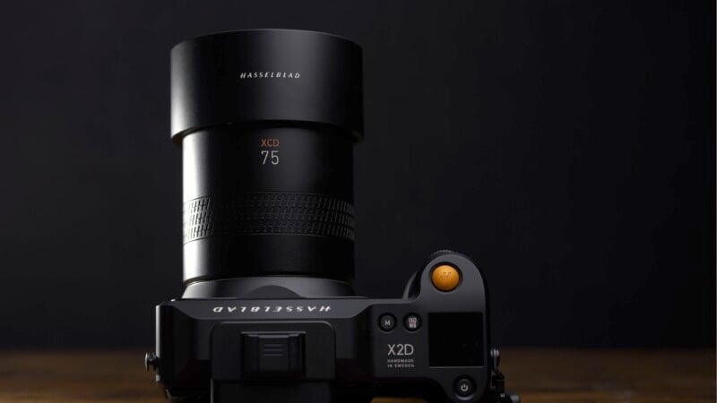 Close-up of a Hasselblad camera with a 75mm XCD lens against a dark background. The focus is on the lens and camera body, highlighting the brand name and details.