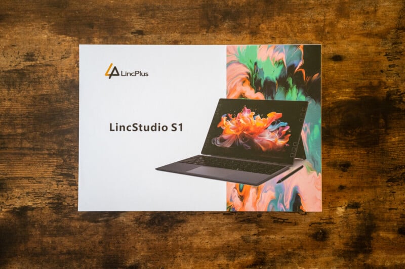 A box displaying the LincPlus LincStudio S1 laptop. The packaging features a vibrant abstract design with splashes of color surrounding an image of the laptop on a wooden surface.