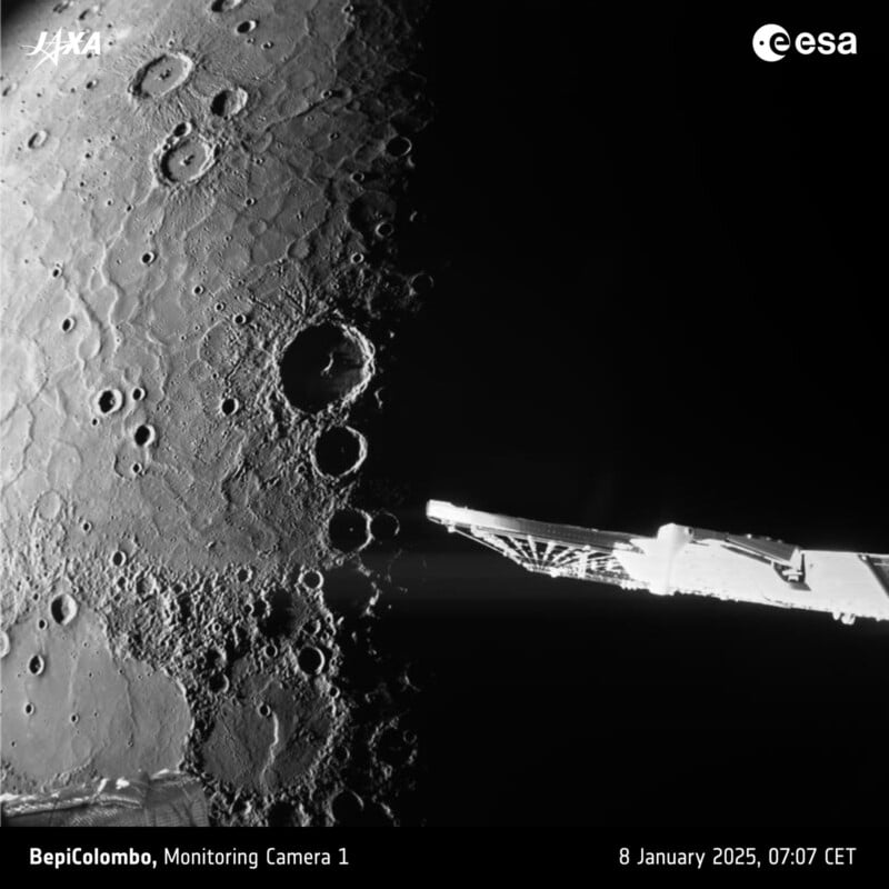 Black and white image of the Moon's surface taken by BepiColombo's Monitoring Camera 1. The surface features craters in varying sizes, with a spacecraft component visible on the right. Timestamp: 8 January 2025, 07:07 CET.