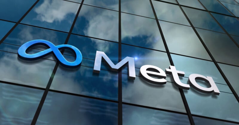 The image shows a building with reflective glass windows, featuring a blue logo resembling an infinity symbol next to the word "Meta" in white letters. The sky and clouds are mirrored on the building's surface.