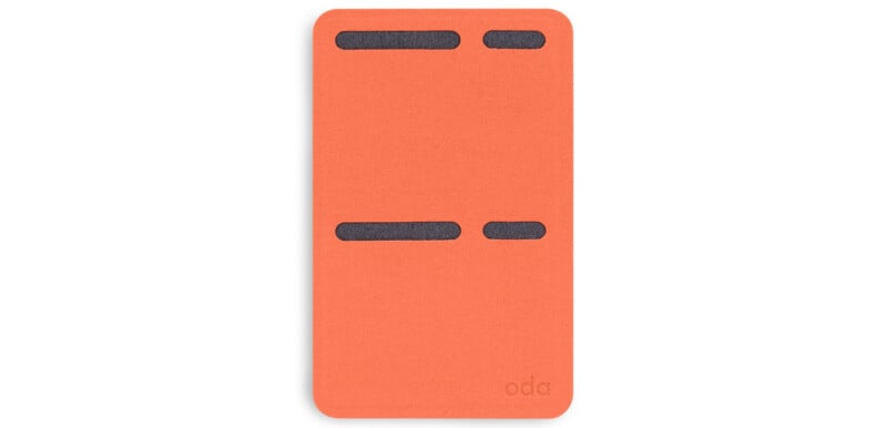 An orange card with rounded edges featuring four horizontal black slits of varying lengths on its surface. The bottom right corner has the word "oda" printed in small font.