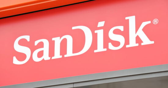 A red sign with the white text "SanDisk" is prominently displayed. The text is in a bold, modern font with a reserved trademark symbol at the top right corner of the letter "k.