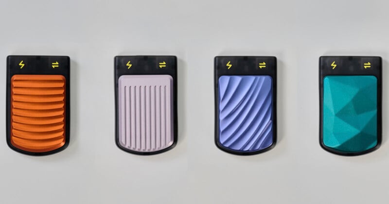 Four textured portable chargers are displayed against a light background. From left to right, they are orange with wavy ridges, gray with vertical ridges, blue with horizontal waves, and teal with a geometric pattern. Each features a lightning bolt symbol.