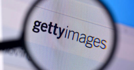 Magnifying glass focusing on the "Getty Images" logo displayed on a computer screen. The text is clear and prominent, indicating the well-known stock photography company.