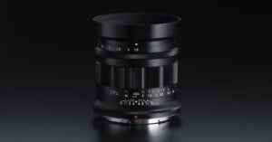 A professional camera lens with a sleek black design on a dark background. It features various focal length markings, including 28 and 2.5, and a range of other settings for precise adjustments.