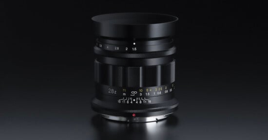 A professional camera lens with a sleek black design on a dark background. It features various focal length markings, including 28 and 2.5, and a range of other settings for precise adjustments.